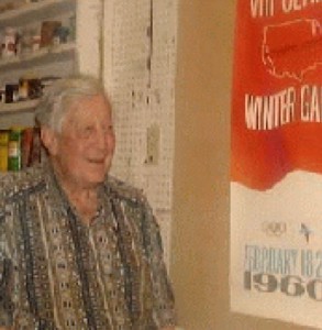 A senior man smiling while looking at a poster on the wall.