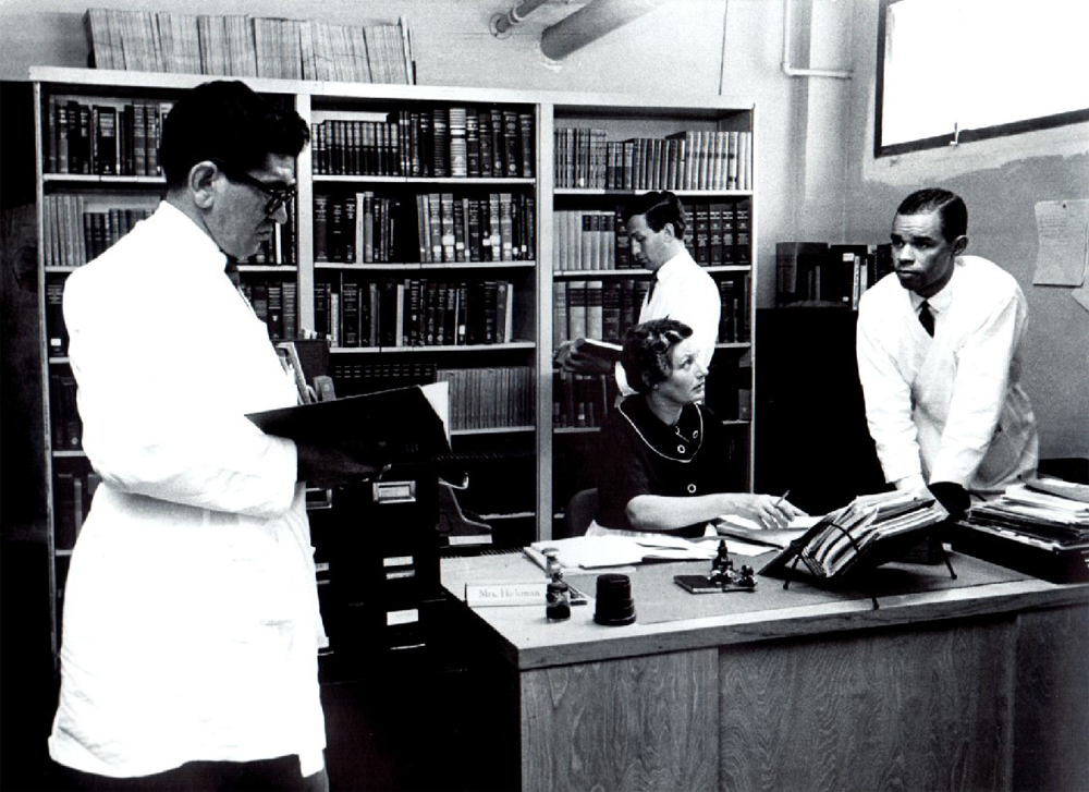 Librarian Mrs. Hickman with physicians in Kaiser Permanente Oakland Medical Center library, circa 1970