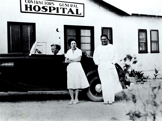 Dr. Garfield (far right) stands with a nurse in front of a car, and Betty Runyen, RN, at the wheel, 1933. 