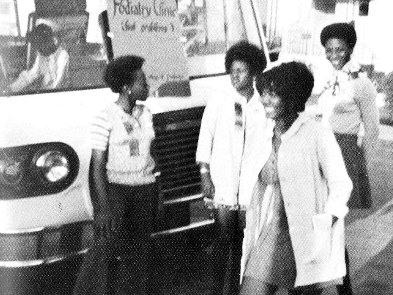 4 young 70s era women nursing students standing in front of a large mobile health van with a sign that reads "podiatry clinic"
