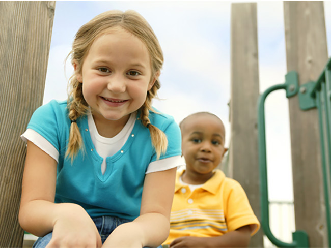 2 children sitting on a playground structure