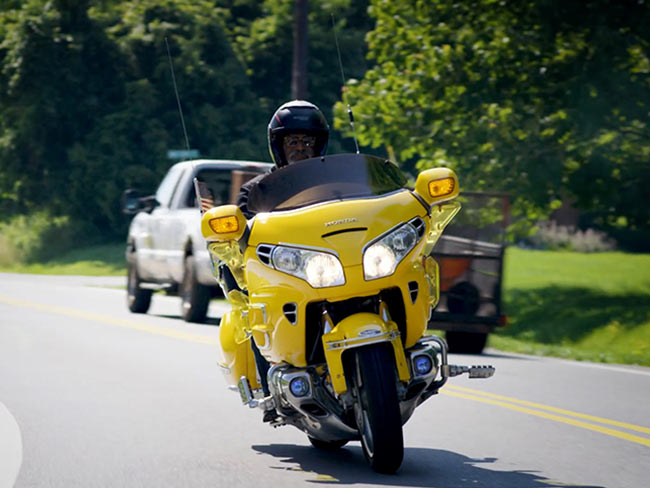 Man riding a yellow motorcycle on a road.