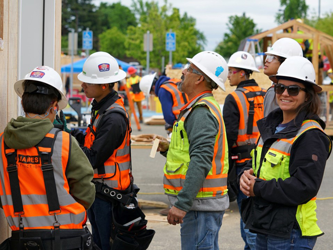 4 persons wearing construction hard hats and safety vests