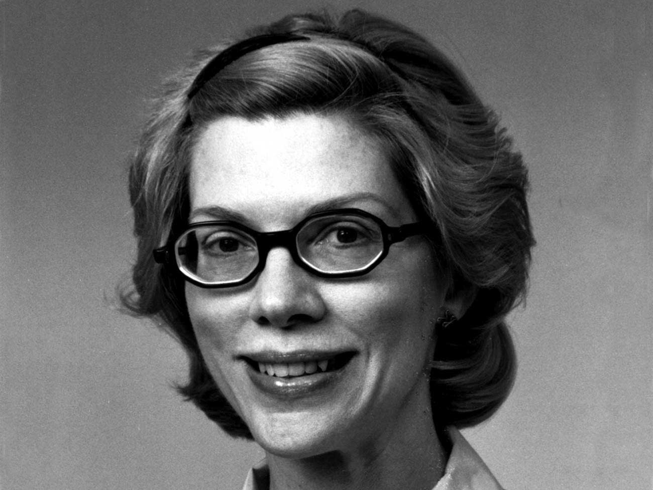 black and white photo of a woman smiling and wearing glasses