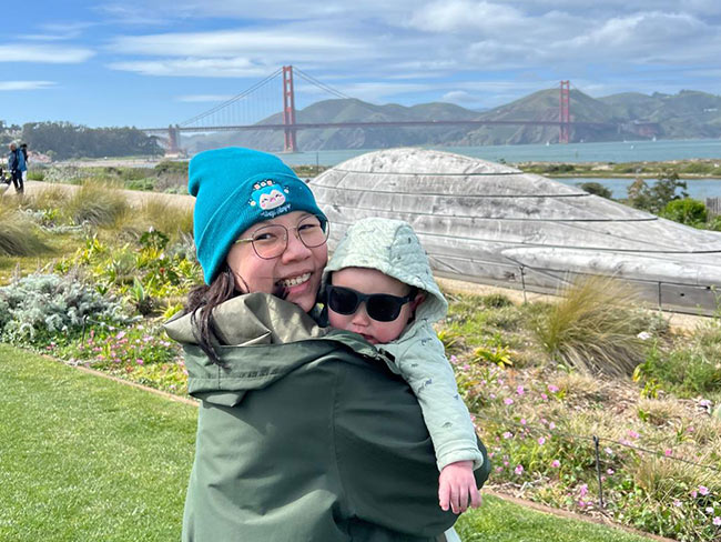 mother holding baby in front of golden gate bridge