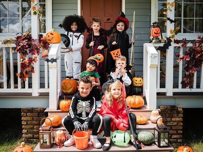 group of children dressed in Halloween costume on front porch of house