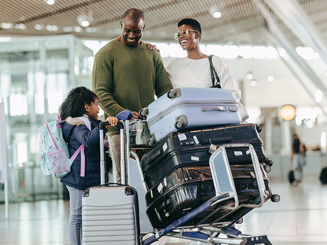 Young happy family walking through airport with luggage