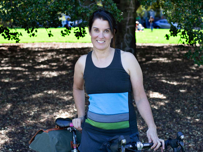 woman standing in a park with bicycle