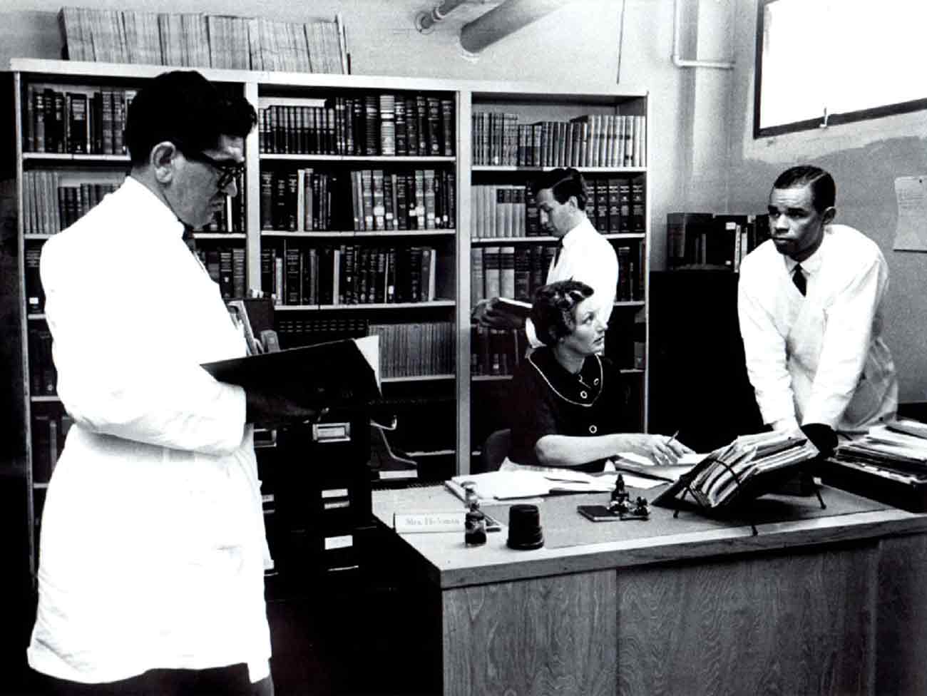 Librarian Mrs. Hickman with physicians in Kaiser Permanente Oakland Medical Center library, circa 1970