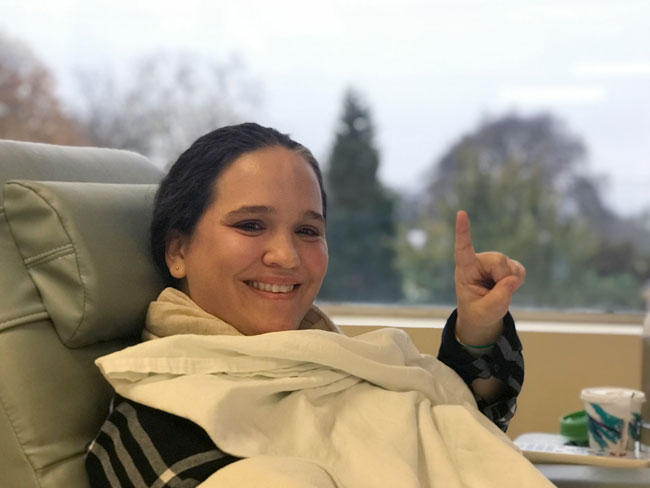 smiling woman on hospital bed making the "victory" sign with her 2 fingers