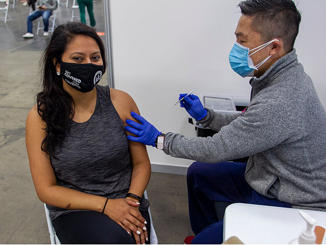 Man gives a woman the vaccine in her left arm. 