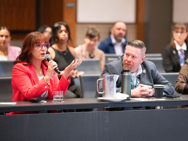 woman seated at table speaking into microphone