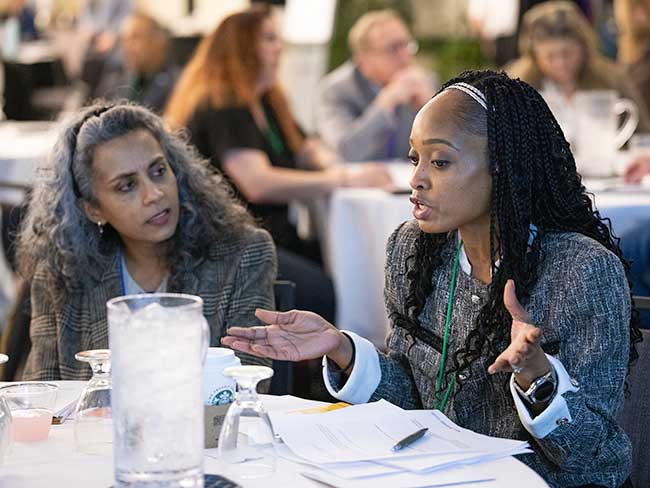 Two women seated at a table having a discussion during a bargaining session. 