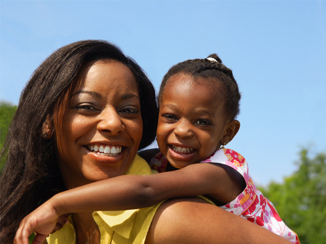 Black mother and her daughter smiling while outdoors