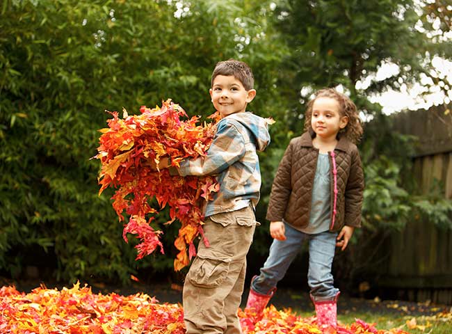 boy and girl playing outside with autum leaves