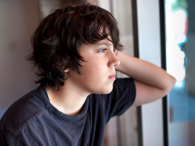 young boy staring pensively out the window