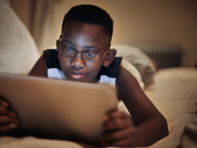 Boy wearing glasses, looking at a tablet