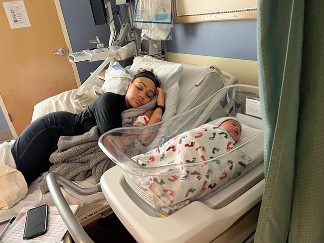 Bree Graham sleeping next to her baby in a hospital room