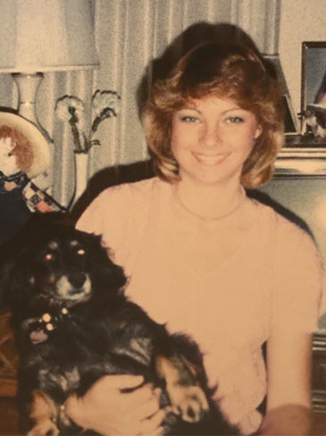 Woman smiling while holding her black dog.