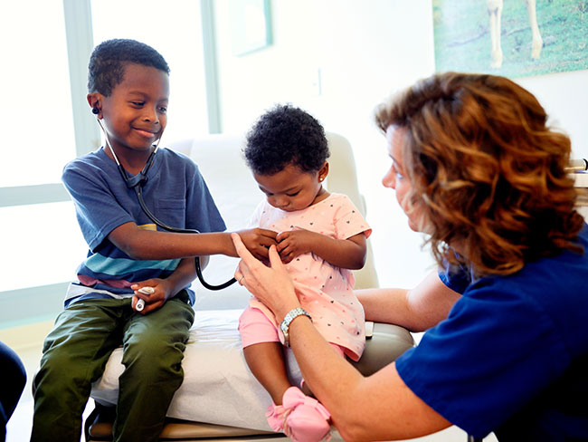 Doctor shows siblings how to use a stethoscope