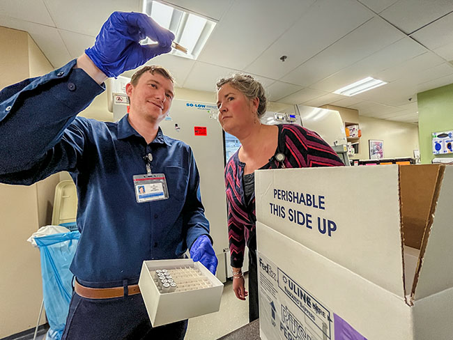 Researchers Matthew Applesmith and Jen McCance, who work on the study with Drs. Bastow and Ellis, load frozen samples for analysis.