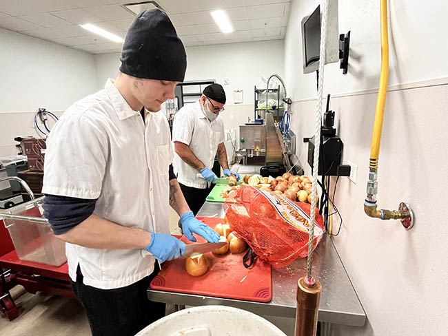 Two men preparing food in an industrial kitchen.