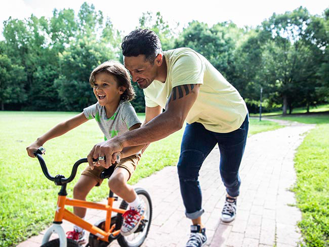 Dad pushing child on tricycle