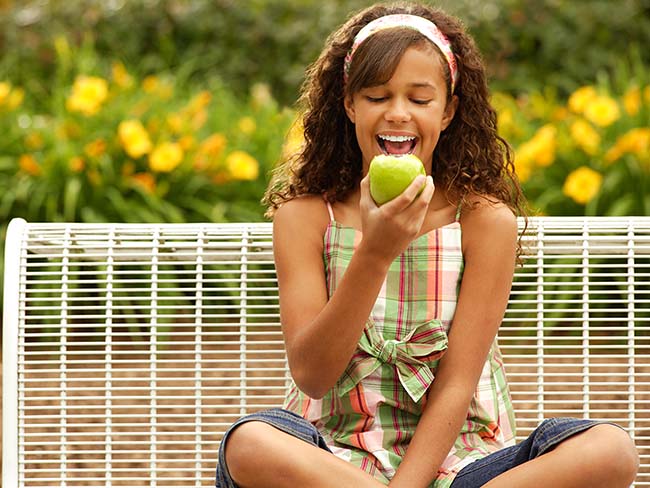 Girl eating an apple outdoors