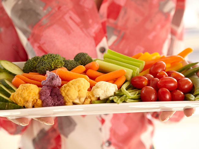 Person holding a platter of healthy vegetables