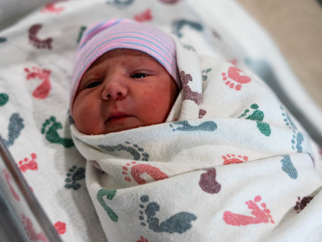 A swaddled newborn baby girl. 