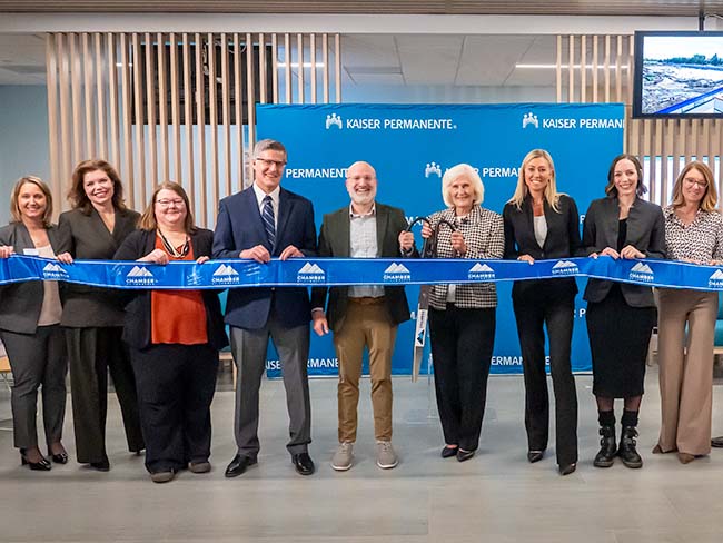 People standing in front of a blue ribbon with a giant pair of scissors