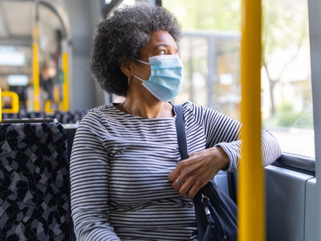 woman seated on bus wearing protective face mask