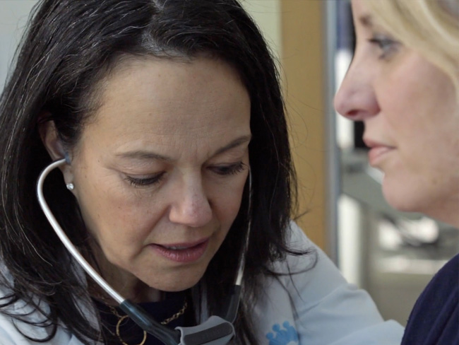 woman using stethoscope to examine a patient