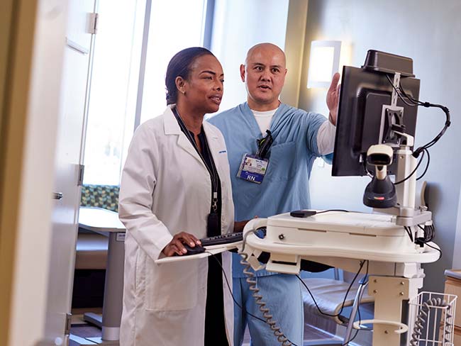 Doctor and nurse in discussion while looking at a monitor,.