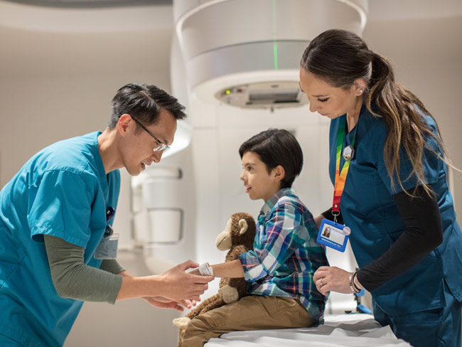 Doctor and technician speaking to child before radiation treatment