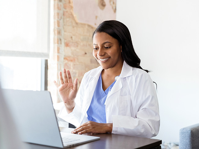 Female doctor waves at patient on video conference