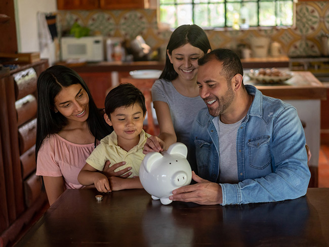 Happy Latin American family saving money in a piggybank