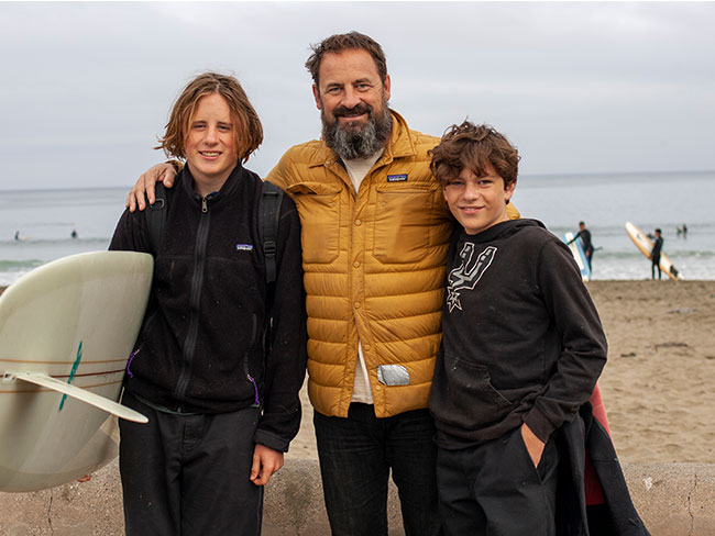Father and sons at beach with a surfboard