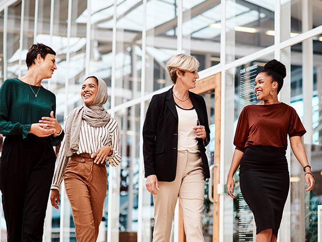 Female coworkers walking and talking outdoors.