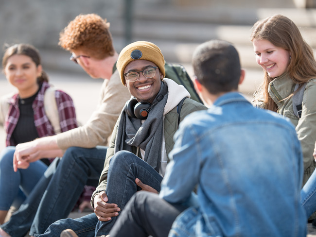 multi ethnic group of university students hanging out outdoors on campus