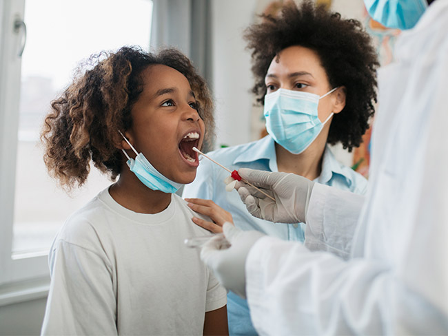 Young Black girl taken into a medical clinic by her mother to get tested for a coronavirus, taking a mouth swab test.