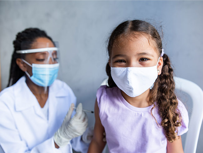 young girl wearing face mask receiving a vaccination