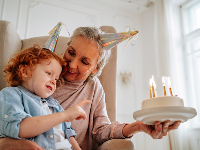 child with grandmother holding birthday cake
