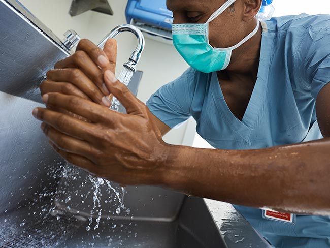 medical worker wearing face mask and scrubs washing hands