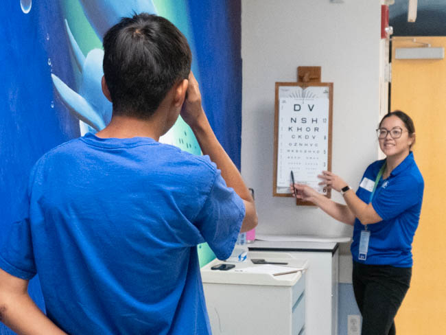 young man in front of eye testing chart