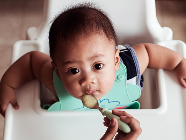 baby in hi-chair eating