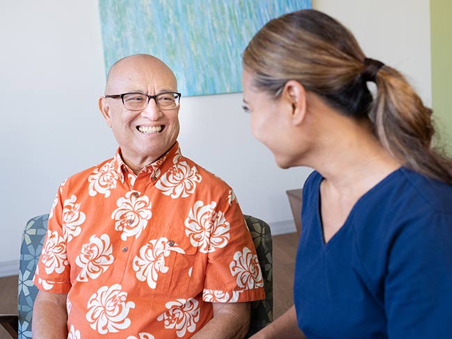 A senior man smiling at a nurse during an exam.