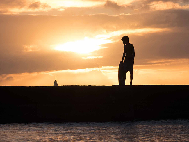 Silhouette of a teenage boy with a body board.