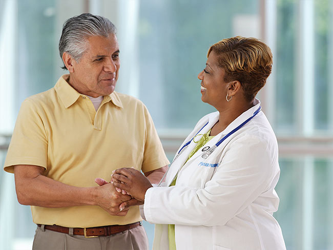 A smiling female physician shaking hands with her senior male patient. 