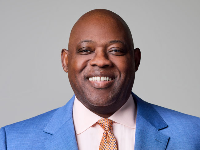 portrait of Kevin Hart smiling wearing suit and tie